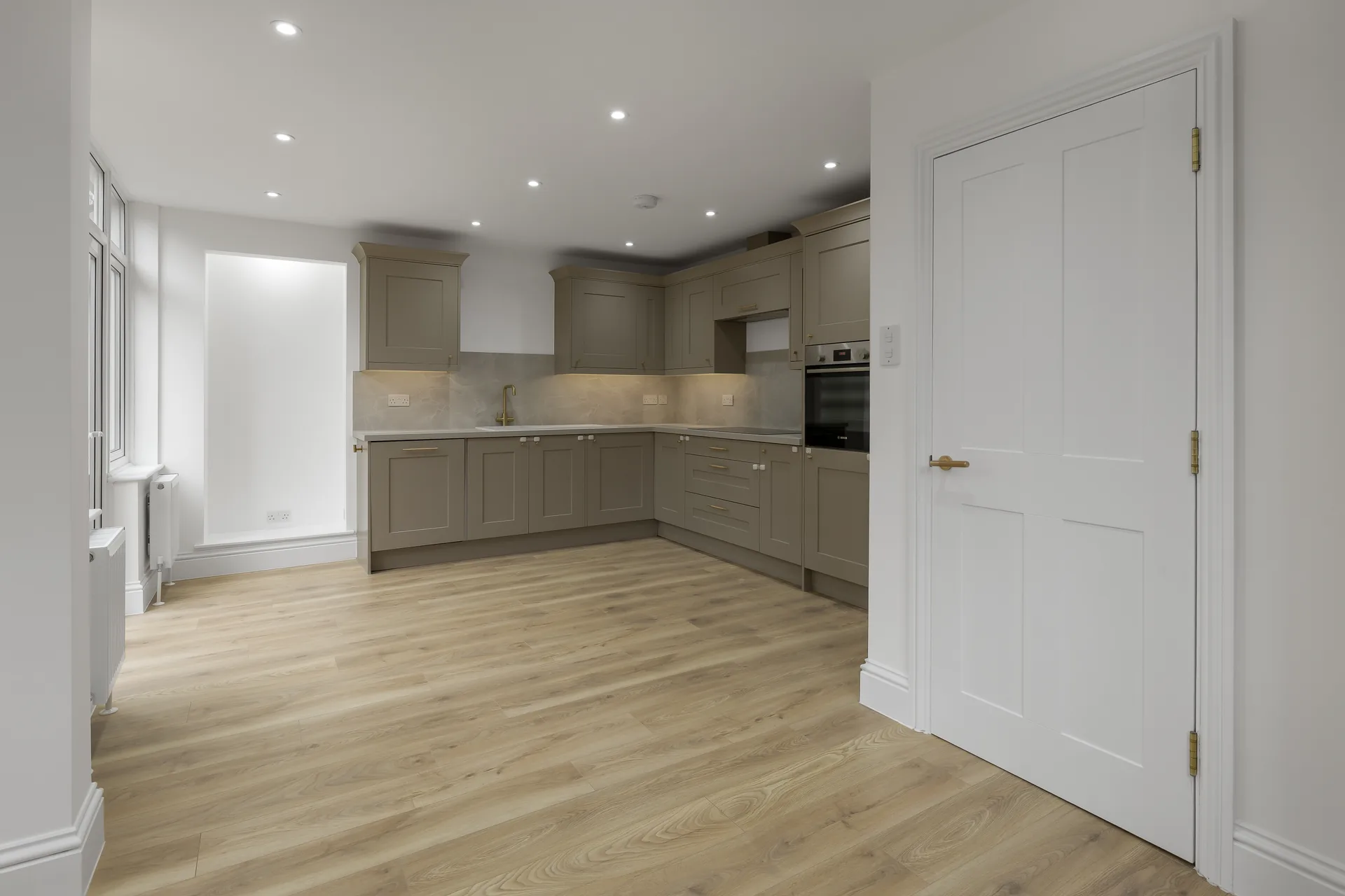 Bright, Open Concept Kitchen And Dining Space With Minimalist Cabinetry And A White Paneled Interior Door.